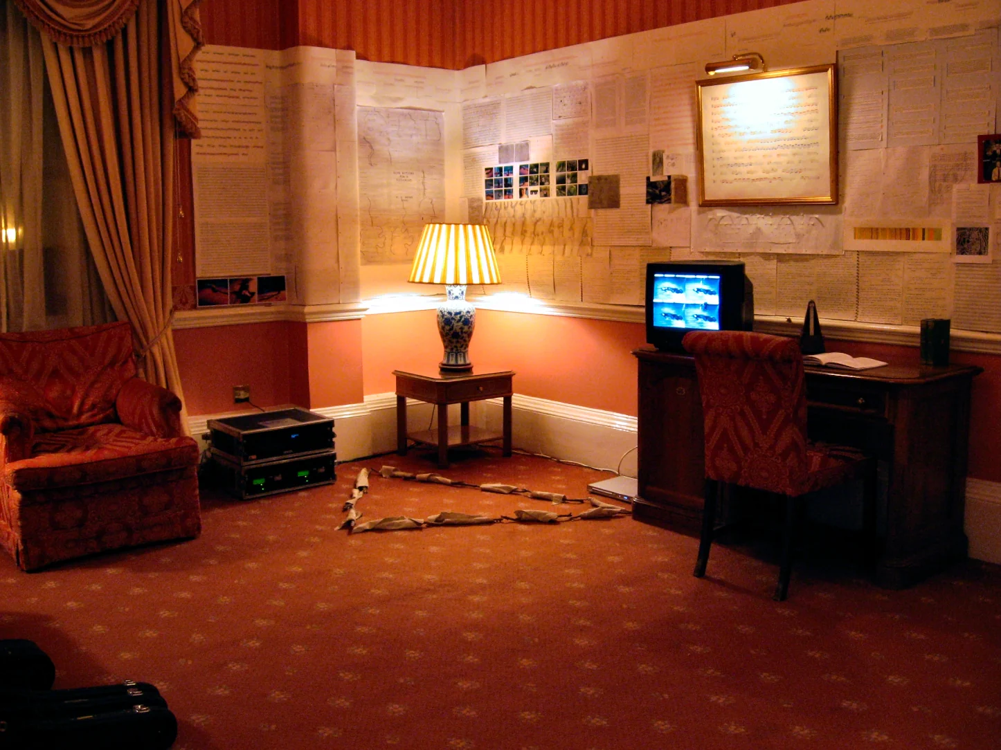 Wide installation view showing documents covering all walls of the hotel suite with audio equipment on the floor, The George Hotel, Huddersfield, 2007