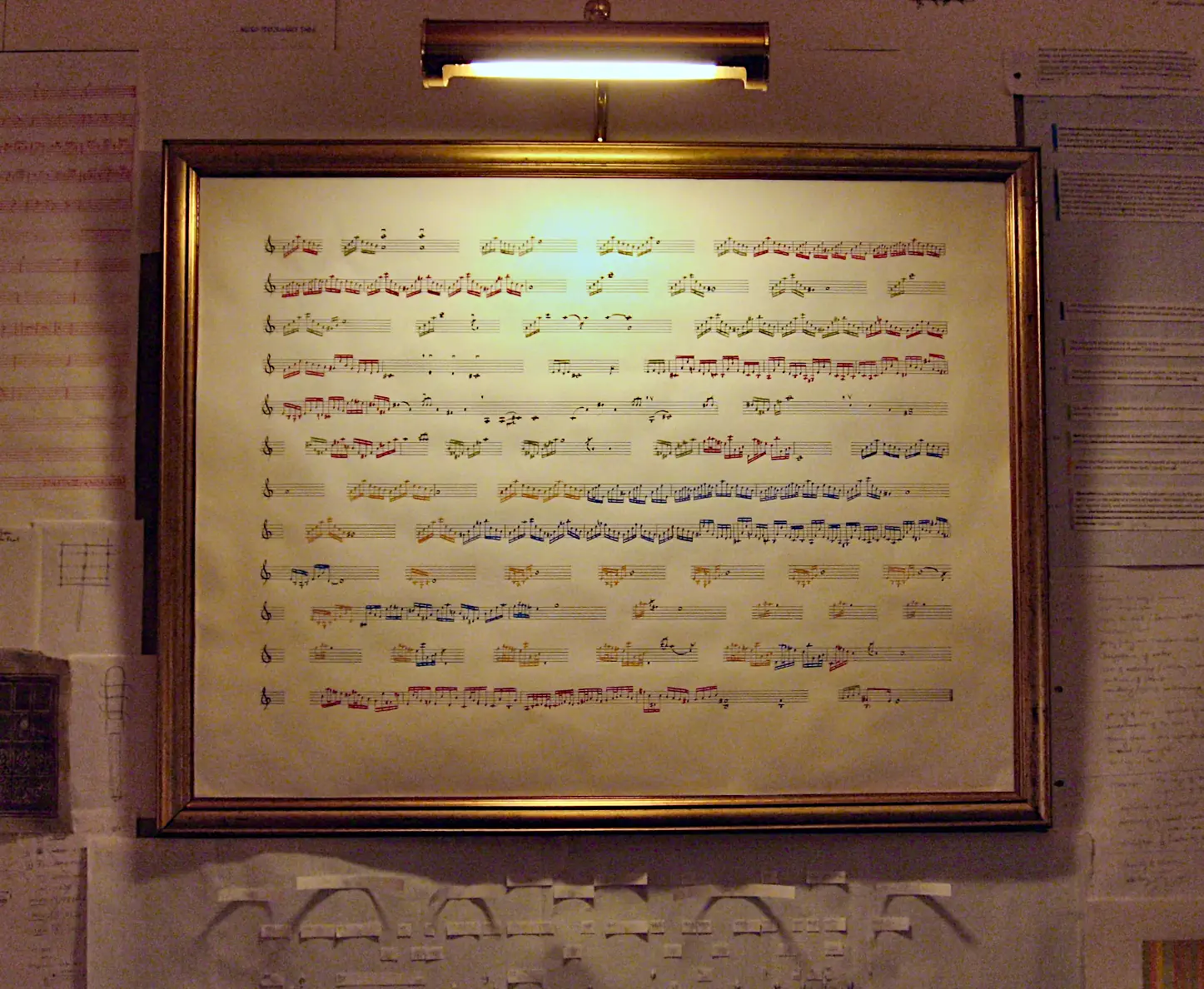 Framed annotated score mounted on the hotel room wall, surrounded by pinned documents and drawings