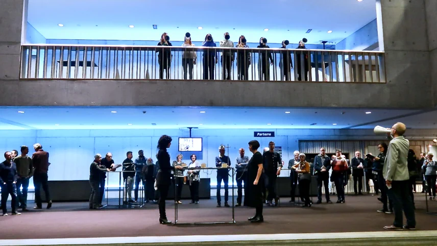 Photograph of the first performance of Structural Cohesion showing singers on a balcony with assembled audience and additional performers on the floor below.
